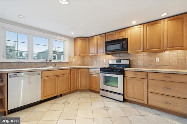 kitchen featuring light tile patterned floors, sink, backsplash, and appliances with stainless steel finishes