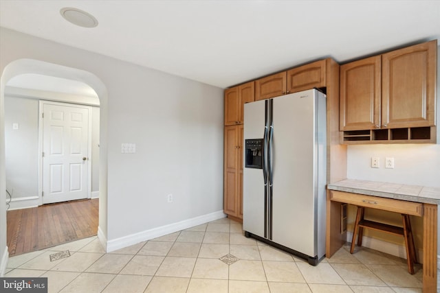 kitchen featuring stainless steel refrigerator with ice dispenser, tile counters, and light tile patterned floors