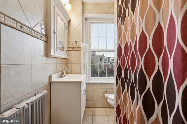 bathroom featuring radiator, tile walls, vanity, tile patterned flooring, and toilet