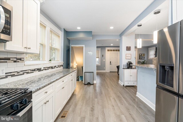 kitchen with white cabinets, hanging light fixtures, and appliances with stainless steel finishes