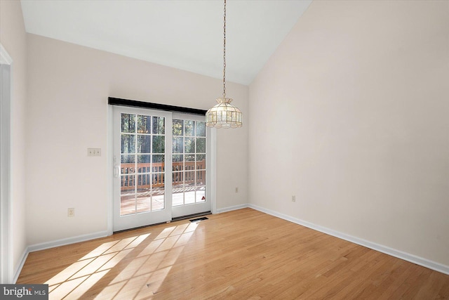 unfurnished dining area featuring hardwood / wood-style floors, vaulted ceiling, and a notable chandelier