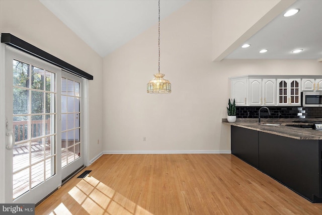 kitchen with pendant lighting, light hardwood / wood-style floors, white cabinetry, and sink