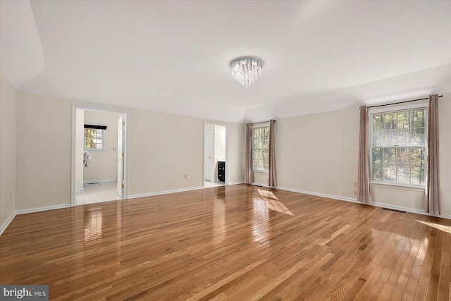 empty room featuring light wood-type flooring and an inviting chandelier