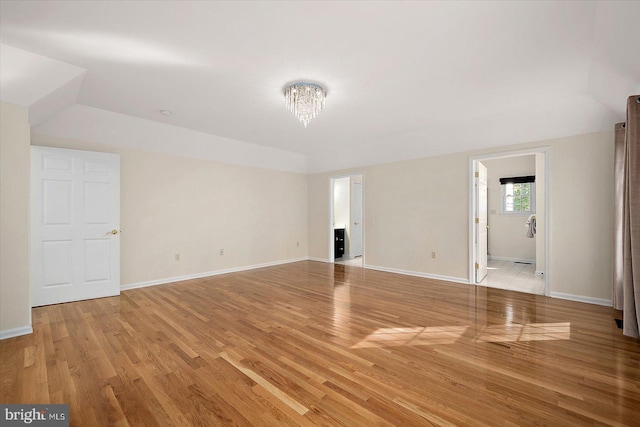 spare room featuring a notable chandelier and light wood-type flooring