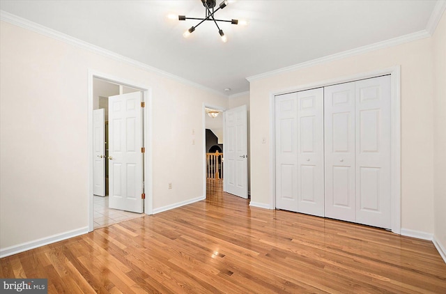 unfurnished bedroom featuring a notable chandelier, a closet, ornamental molding, and light hardwood / wood-style flooring