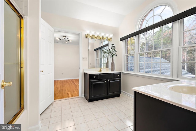 bathroom with tile patterned flooring, vanity, a shower with shower door, and a notable chandelier