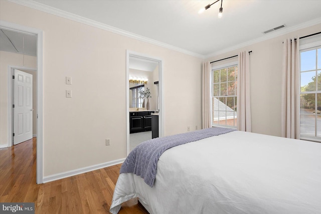 bedroom featuring connected bathroom, light hardwood / wood-style flooring, and ornamental molding