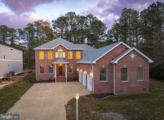 view of front of property featuring central AC, a yard, and a garage