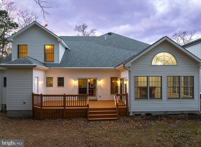 back house at dusk featuring a deck