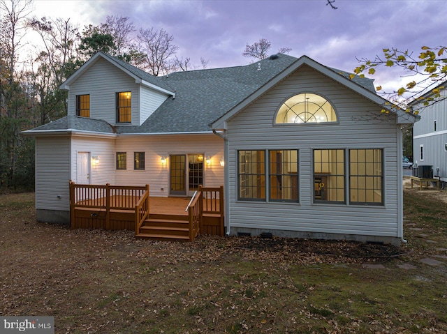 back house at dusk featuring central AC unit and a deck