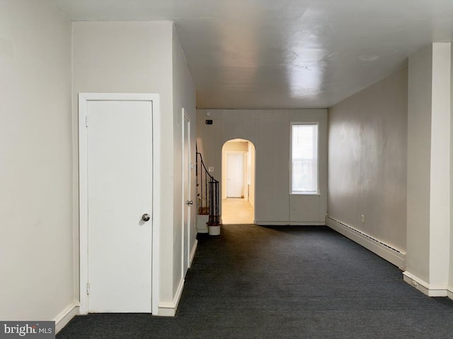 spare room featuring a baseboard radiator and dark carpet