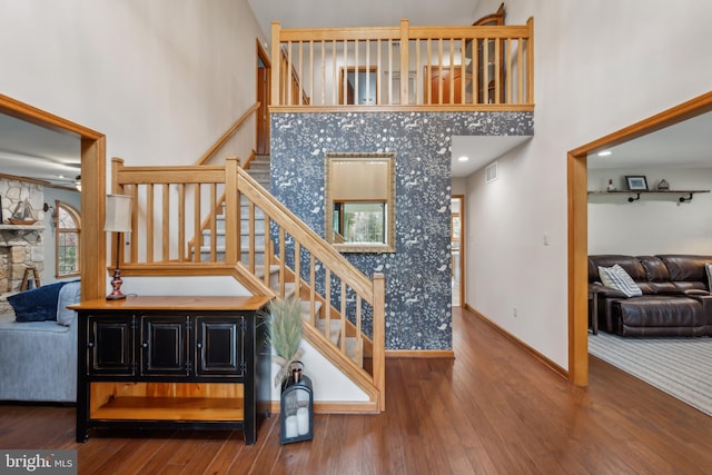 stairway with hardwood / wood-style floors, ceiling fan, and a high ceiling