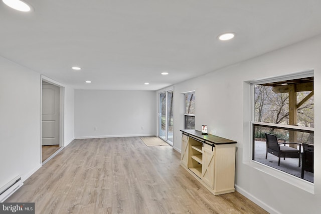 unfurnished living room featuring light hardwood / wood-style floors and a baseboard heating unit