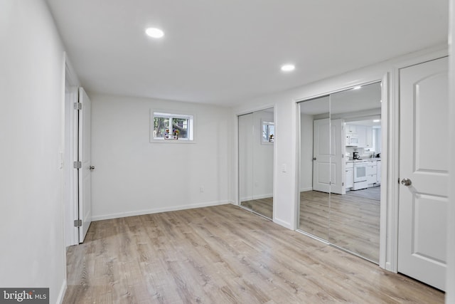 unfurnished bedroom featuring light wood-type flooring and multiple closets