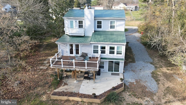 rear view of property with french doors, a balcony, and a wooden deck