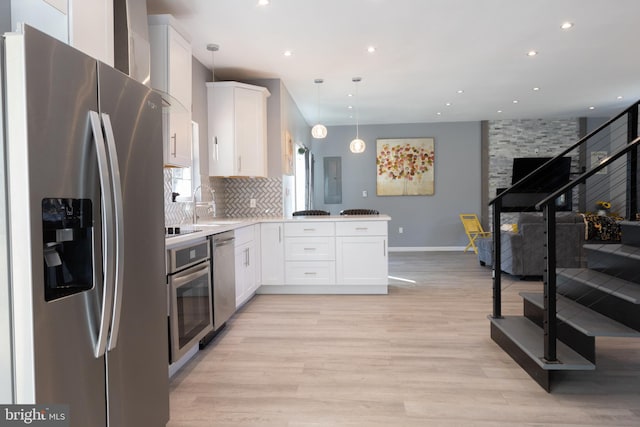 kitchen with stainless steel appliances, white cabinetry, pendant lighting, and kitchen peninsula