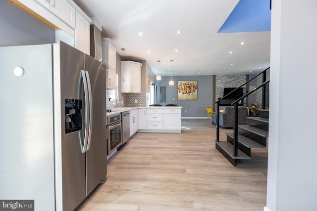 kitchen with stainless steel appliances, white cabinetry, kitchen peninsula, hanging light fixtures, and light hardwood / wood-style flooring