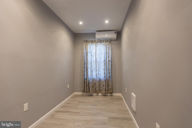 unfurnished room featuring an AC wall unit and light hardwood / wood-style floors