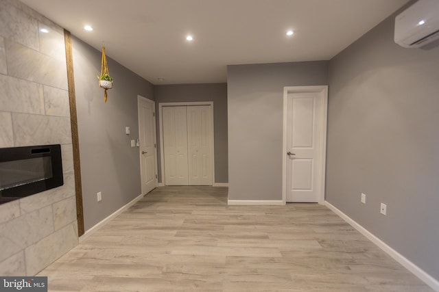 interior space with heating unit, a wall mounted air conditioner, and light hardwood / wood-style floors