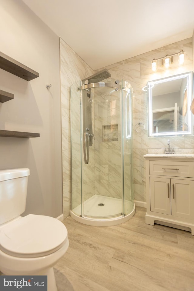 bathroom with an enclosed shower, wood-type flooring, toilet, and vanity