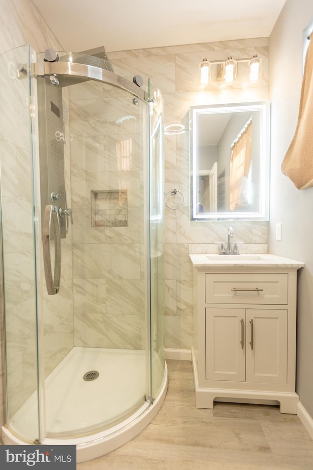 bathroom with walk in shower, hardwood / wood-style floors, and vanity