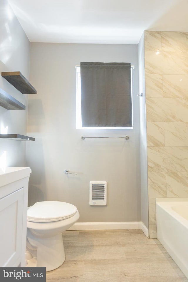 bathroom with toilet, vanity, heating unit, and hardwood / wood-style flooring