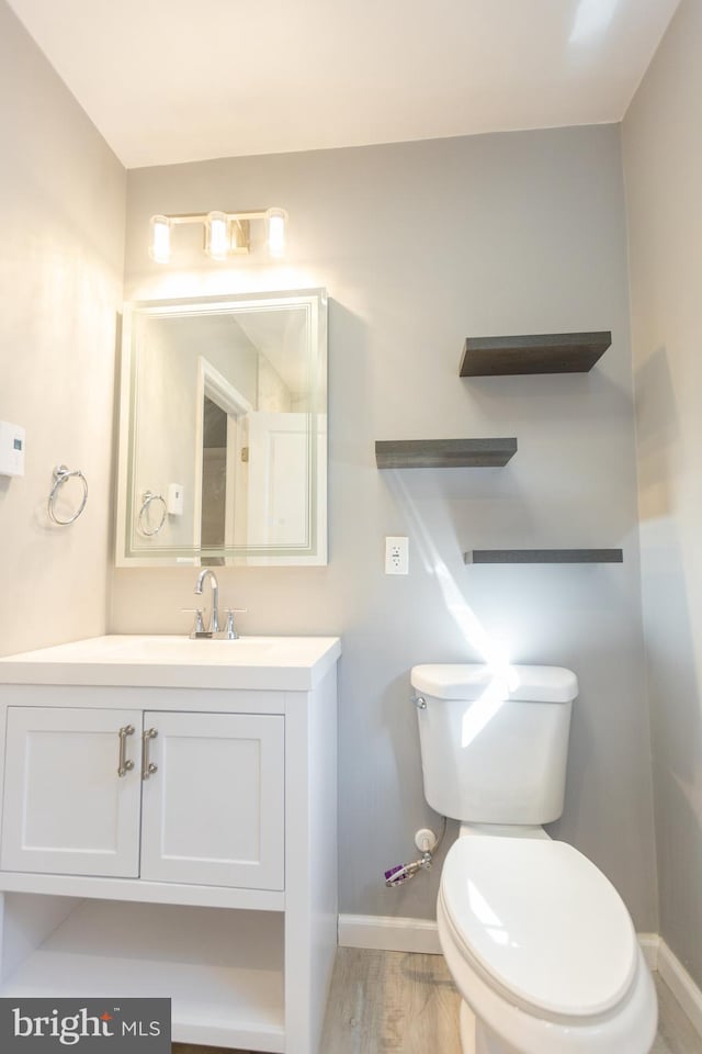 bathroom with hardwood / wood-style floors, vanity, and toilet