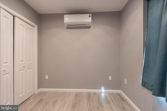 interior space with a closet, light wood-type flooring, and a wall mounted air conditioner