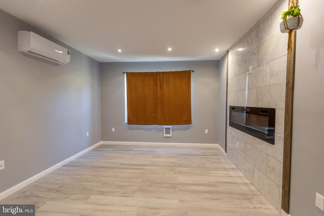 unfurnished room featuring a wall mounted AC and light hardwood / wood-style flooring