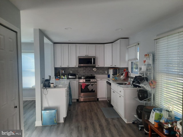 kitchen featuring stainless steel appliances, white cabinetry, dark hardwood / wood-style flooring, decorative backsplash, and sink