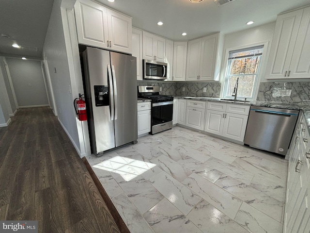 kitchen featuring stainless steel appliances, white cabinetry, tasteful backsplash, and sink