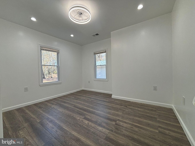 empty room featuring dark wood finished floors, recessed lighting, and baseboards