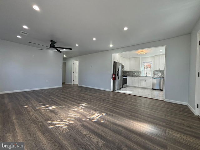 unfurnished living room with dark hardwood / wood-style flooring, ceiling fan, and sink