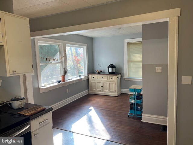 kitchen with dark countertops, baseboards, electric range oven, white cabinets, and dark wood-style flooring