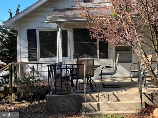 exterior space with outdoor dining area, a shingled roof, and a patio area