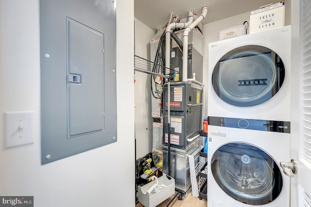 laundry area with light wood-type flooring, stacked washer and dryer, and electric panel