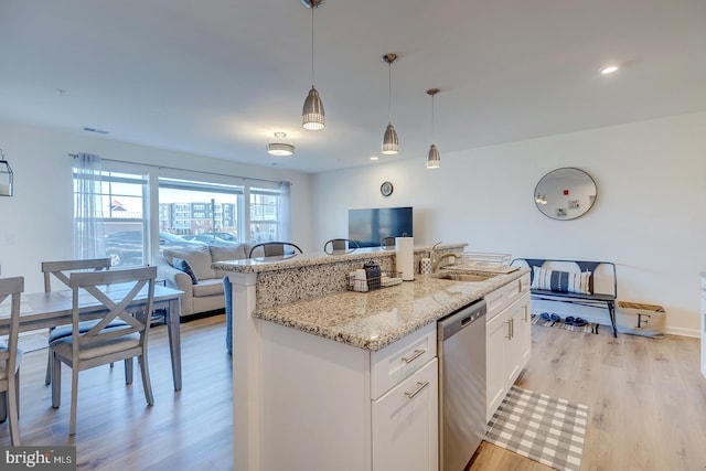 kitchen featuring dishwasher, a center island with sink, hanging light fixtures, light hardwood / wood-style flooring, and white cabinetry