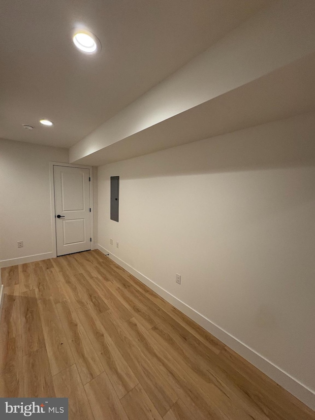 basement with electric panel and light hardwood / wood-style floors