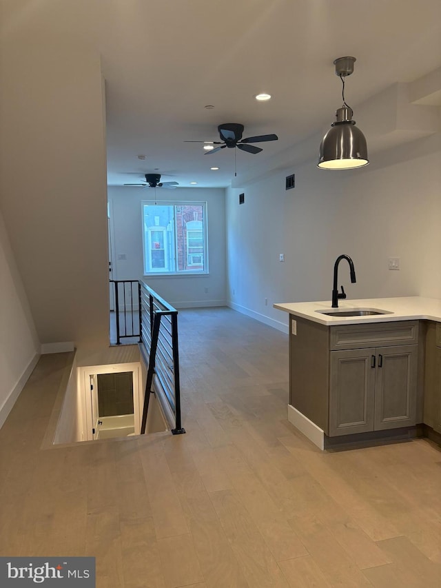 kitchen featuring decorative light fixtures, gray cabinets, sink, and light hardwood / wood-style flooring