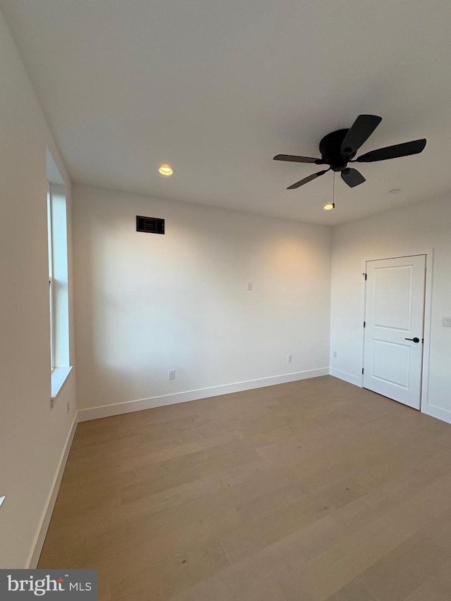 empty room with ceiling fan and light hardwood / wood-style floors