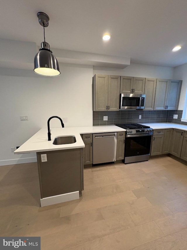 kitchen featuring kitchen peninsula, tasteful backsplash, stainless steel appliances, sink, and hanging light fixtures