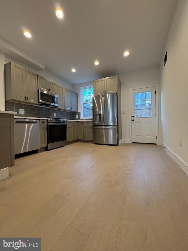 kitchen with light hardwood / wood-style floors, backsplash, and appliances with stainless steel finishes