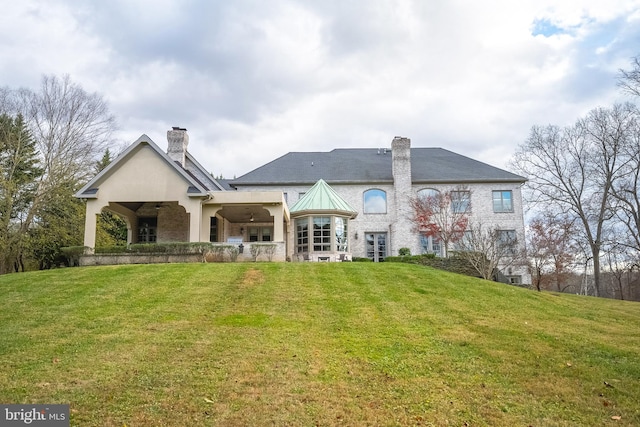 back of property featuring a yard and ceiling fan