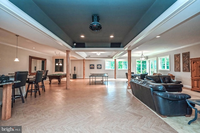 living room featuring decorative columns, a raised ceiling, ornamental molding, and light parquet flooring