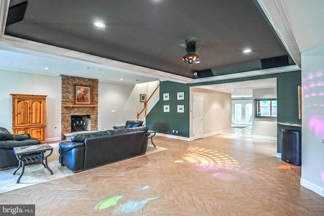 living room featuring a raised ceiling, ceiling fan, ornamental molding, a fireplace, and light parquet flooring