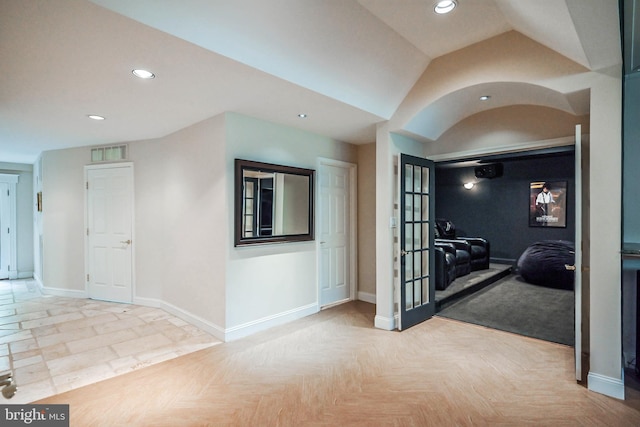 corridor with light parquet flooring and vaulted ceiling