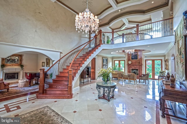 foyer featuring french doors, a towering ceiling, ornamental molding, light tile patterned floors, and a notable chandelier