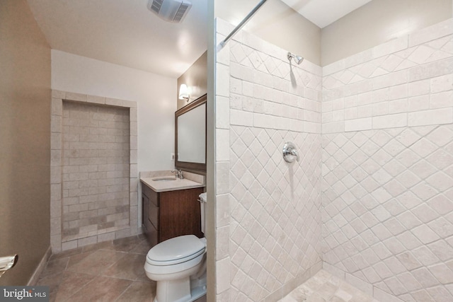 bathroom featuring tile patterned floors, vanity, toilet, and a tile shower