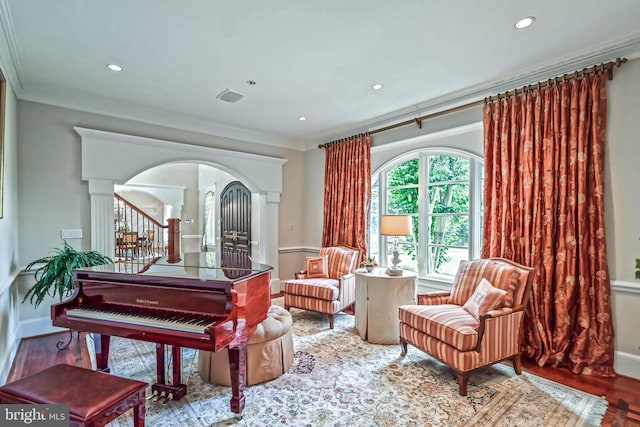 sitting room with wood-type flooring, crown molding, and decorative columns