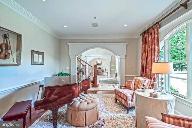 sitting room featuring hardwood / wood-style floors, decorative columns, crown molding, and a chandelier